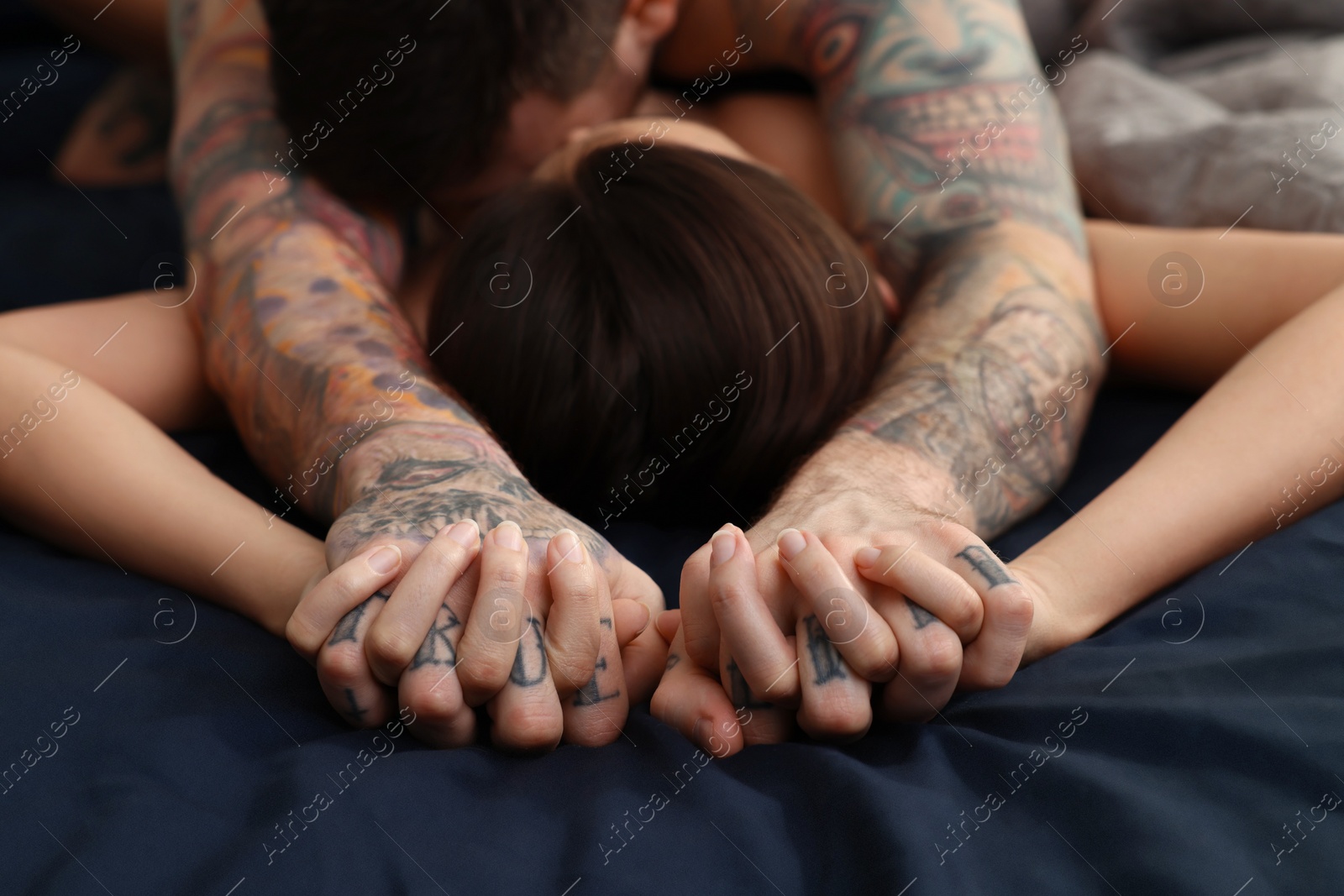 Photo of Passionate couple having sex on bed, focus on hands