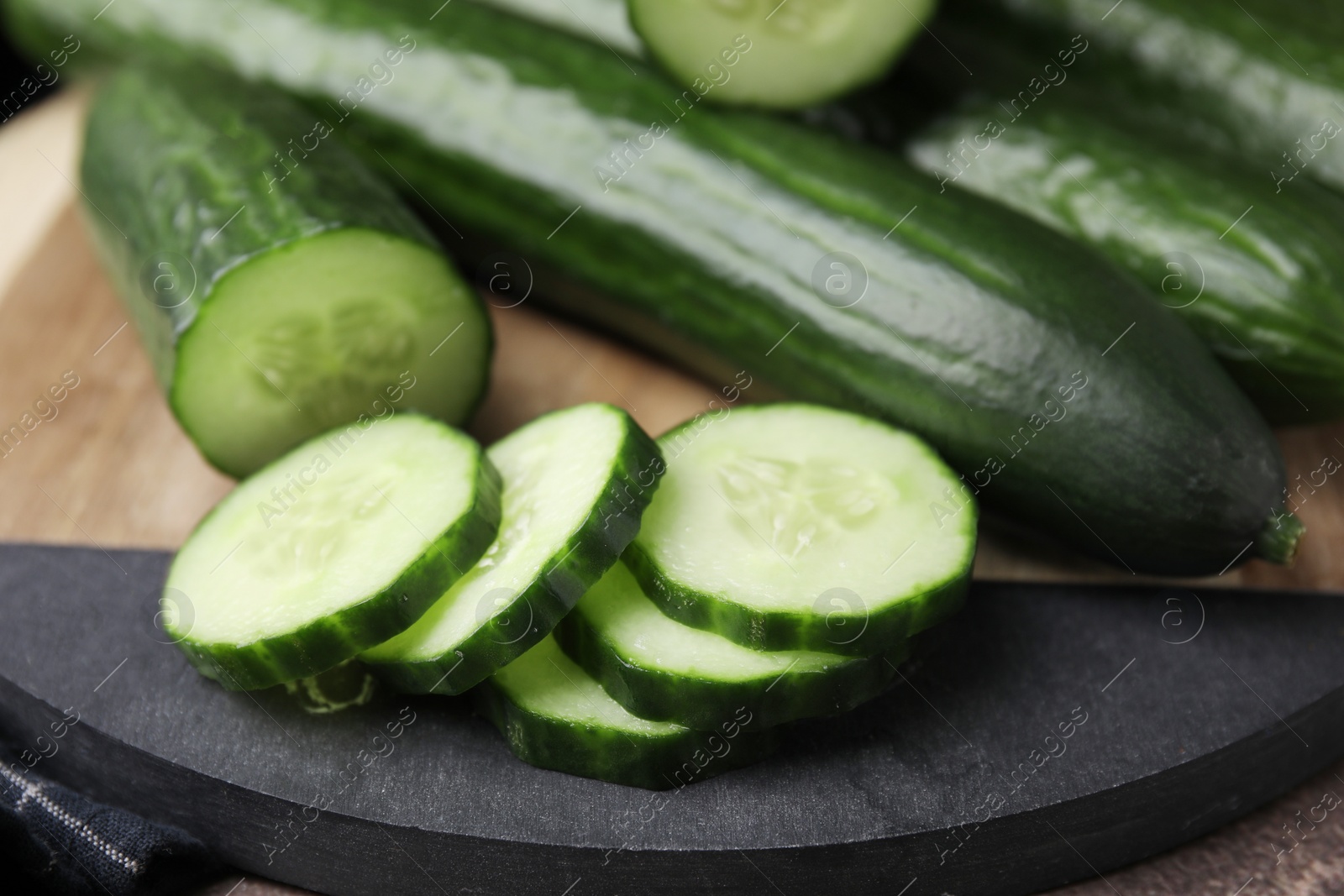 Photo of Fresh whole and cut cucumbers on table, closeup