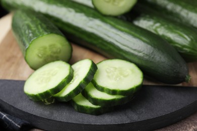 Photo of Fresh whole and cut cucumbers on table, closeup