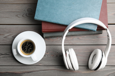 Photo of Books, coffee and headphones on light grey wooden table, flat lay