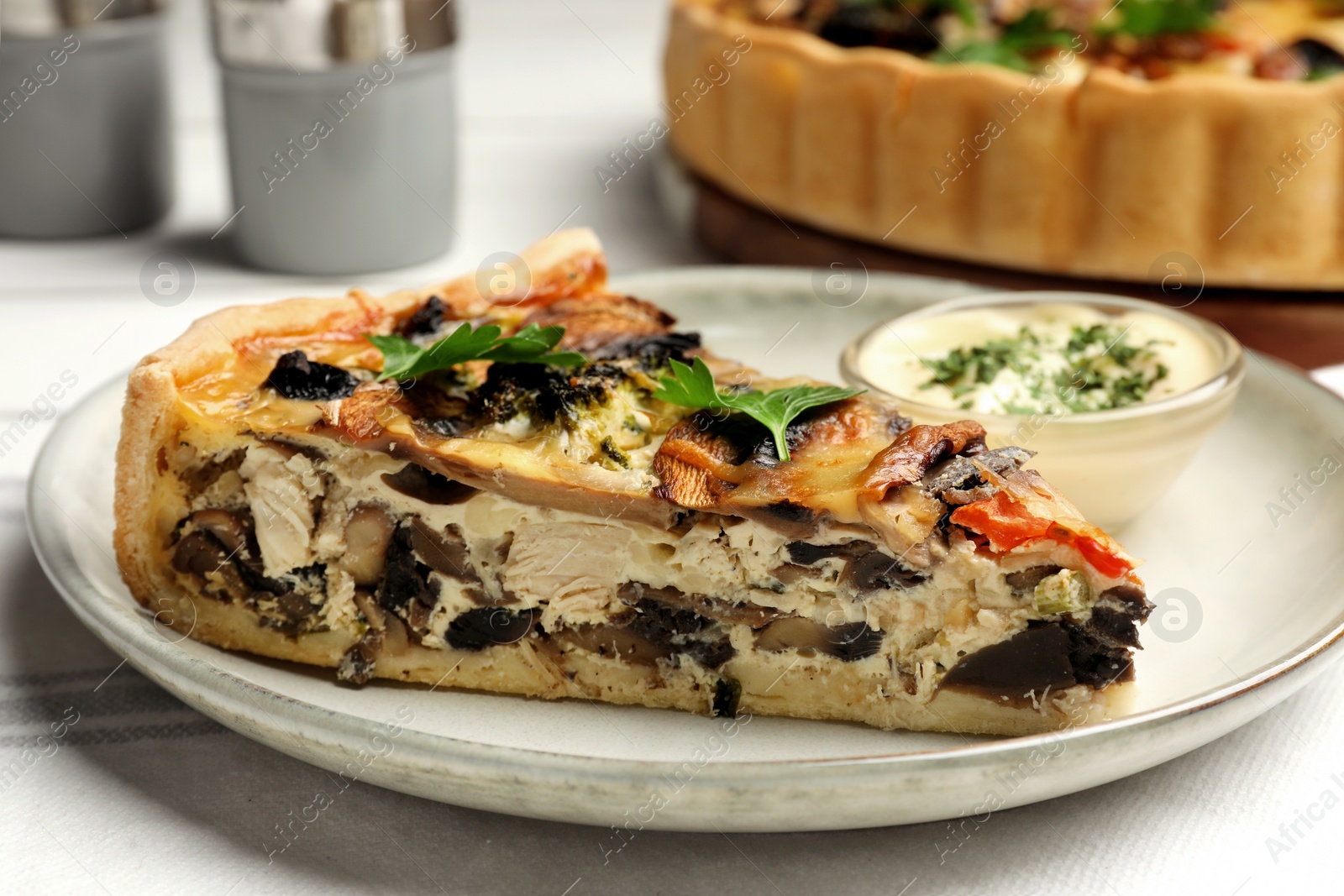 Photo of Piece of delicious quiche with mushrooms and parsley served on white table, closeup