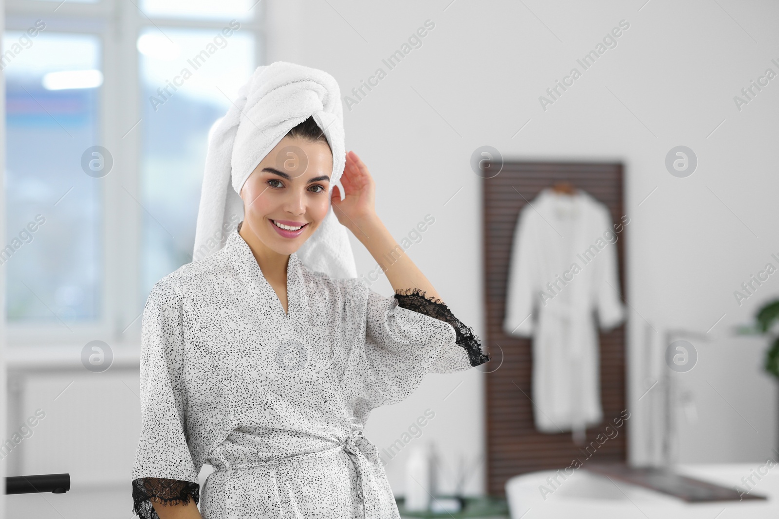 Photo of Beautiful happy woman wearing stylish bathrobe in bathroom