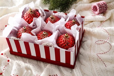 Box with red Christmas baubles on knitted plaid