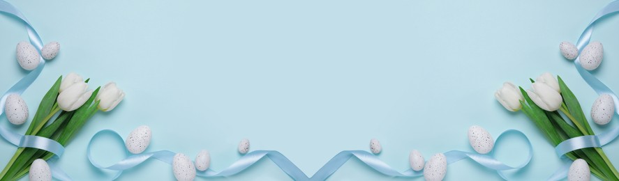 Image of Flat lay composition with decorated Easter eggs and flowers on pale light blue background, space for text. Banner design
