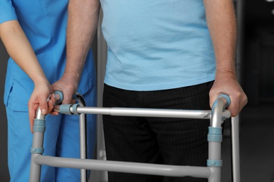 Photo of Nurse assisting senior patient with walker in hospital, closeup