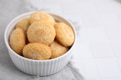 Photo of Tasty sugar cookies in bowl on white tiled table, closeup. Space for text