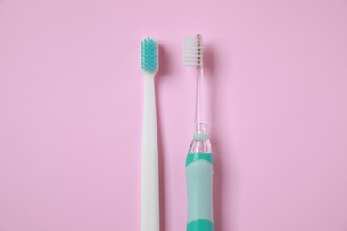Photo of Electric and plastic toothbrushes on pink background, flat lay
