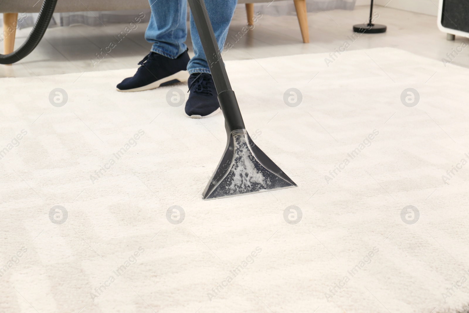 Photo of Man removing dirt from carpet with vacuum cleaner indoors, closeup