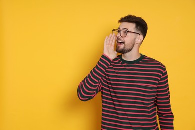 Handsome man in striped sweatshirt screaming on yellow background, space for text