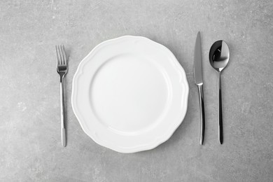 Photo of Ceramic plate and silver cutlery on grey table, flat lay