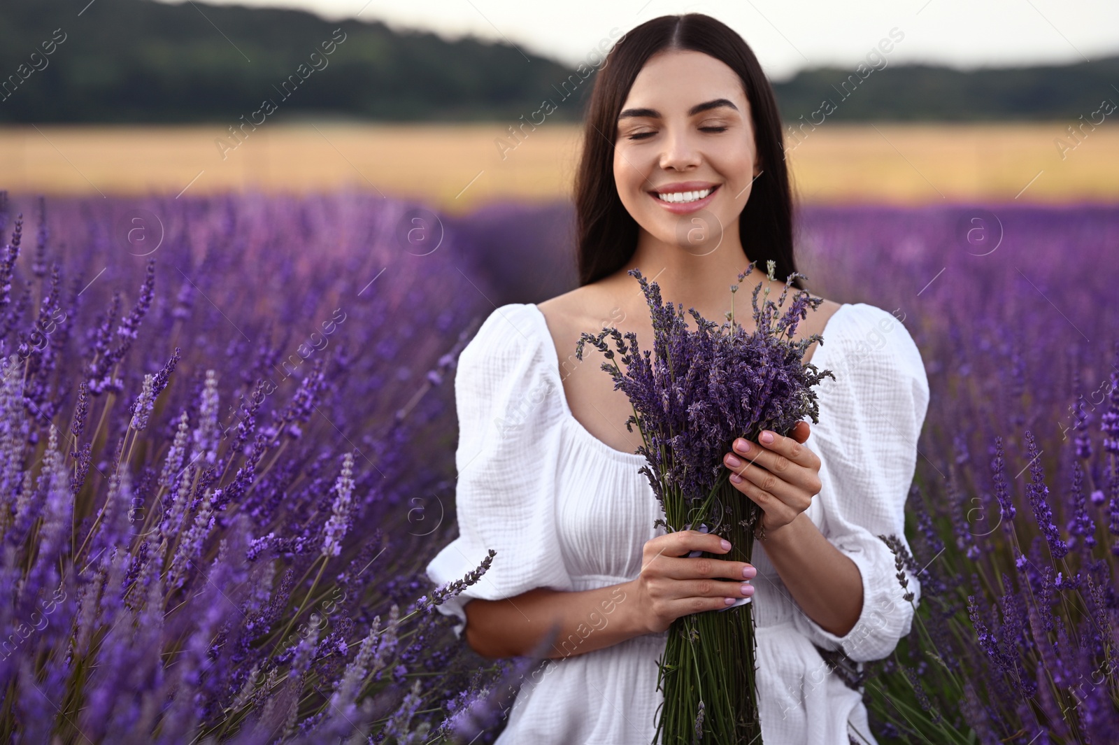 Photo of Beautiful young woman with bouquet in lavender field