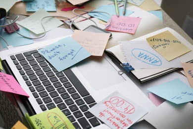 Laptop, notes and office stationery in mess on desk. Overwhelmed with work