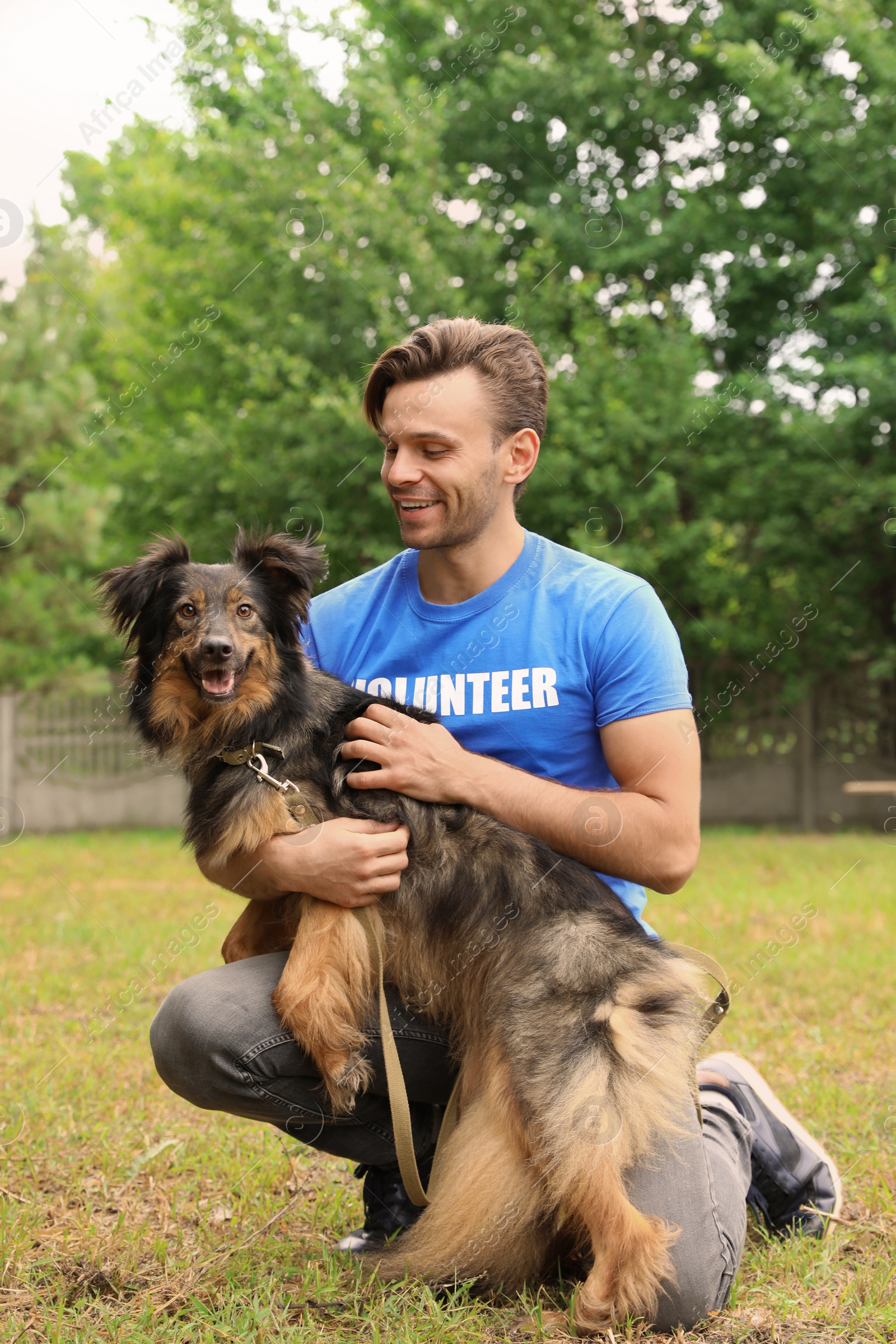 Photo of Male volunteer with homeless dog at animal shelter outdoors