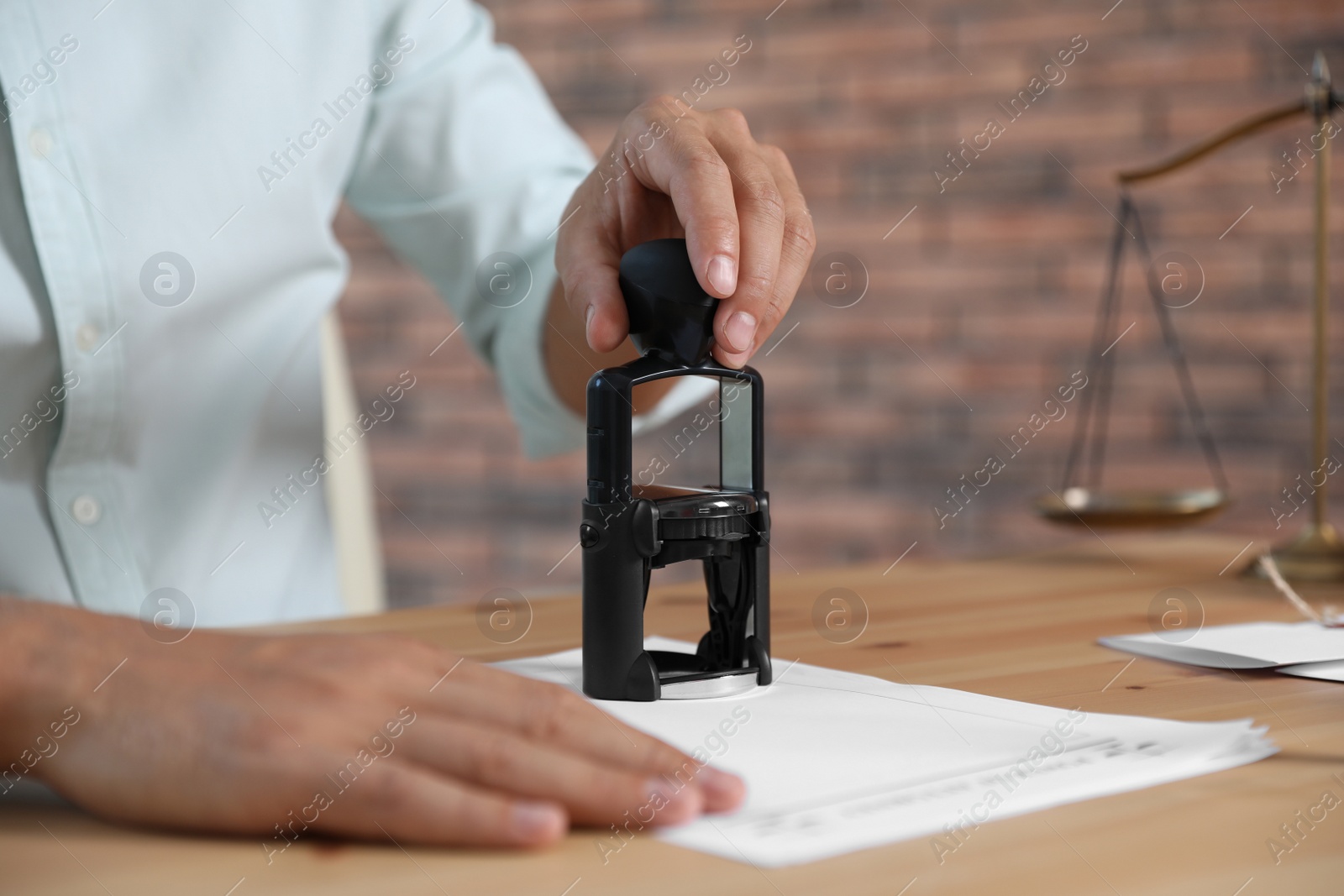 Photo of Male notary stamping document at table, closeup. Space for text