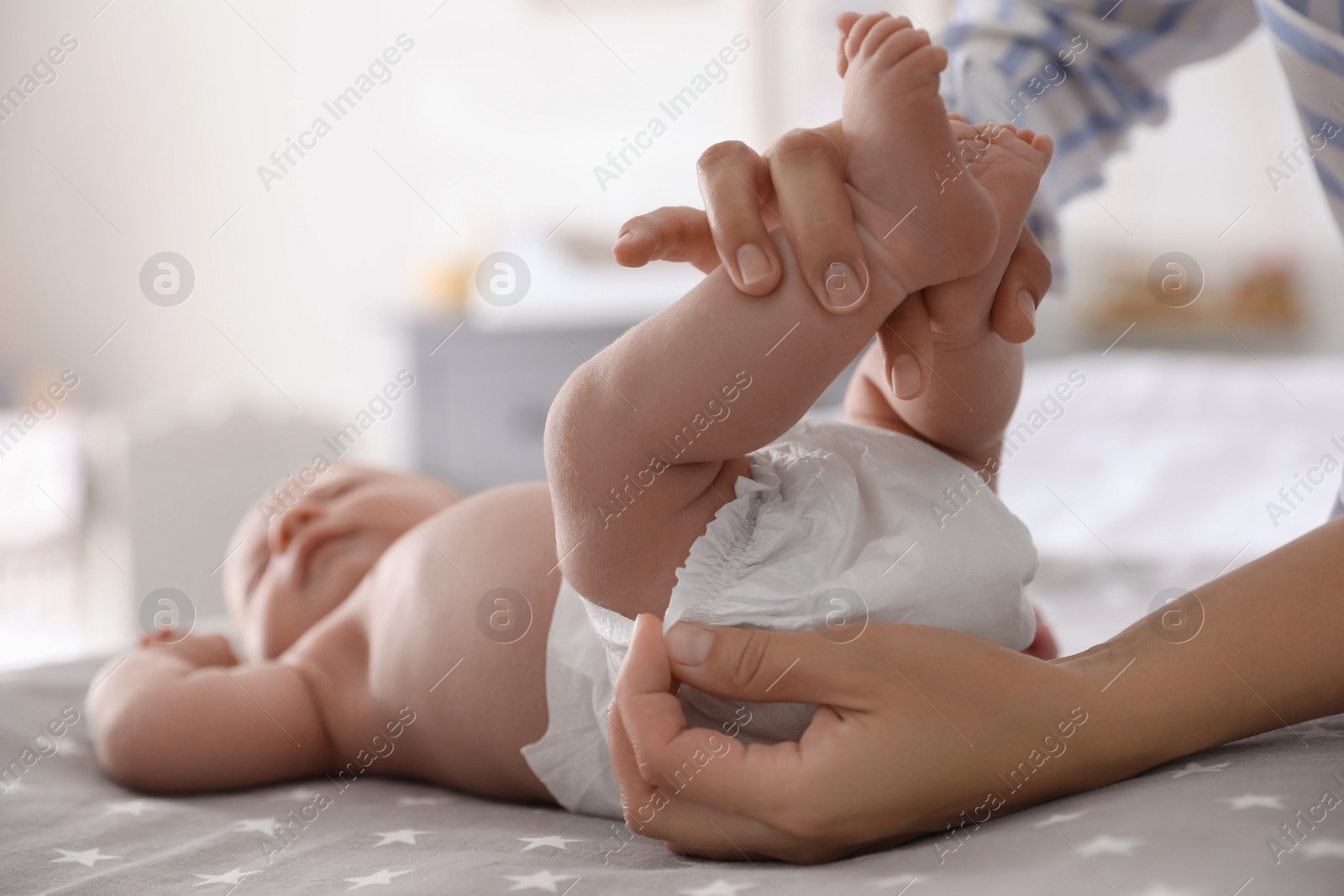 Photo of Mother changing her baby's diaper on bed