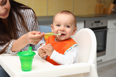 Young mother feeding her little baby at home