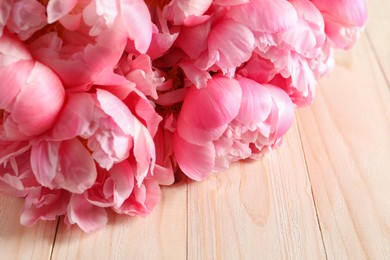 Beautiful pink peonies on wooden table, closeup. Space for text