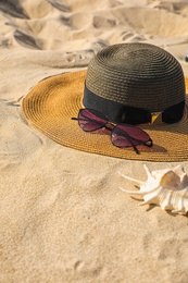 Stylish hat and sunglasses on sand, space for text. Beach accessories