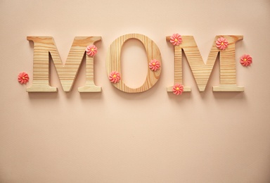 Photo of Word MOM made of wooden letters and flowers on light background, top view. Mother's Day congratulation