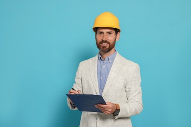 Photo of Professional engineer in hard hat with clipboard on light blue background