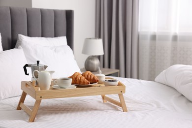 Photo of Tray with tasty breakfast on bed at home, space for text