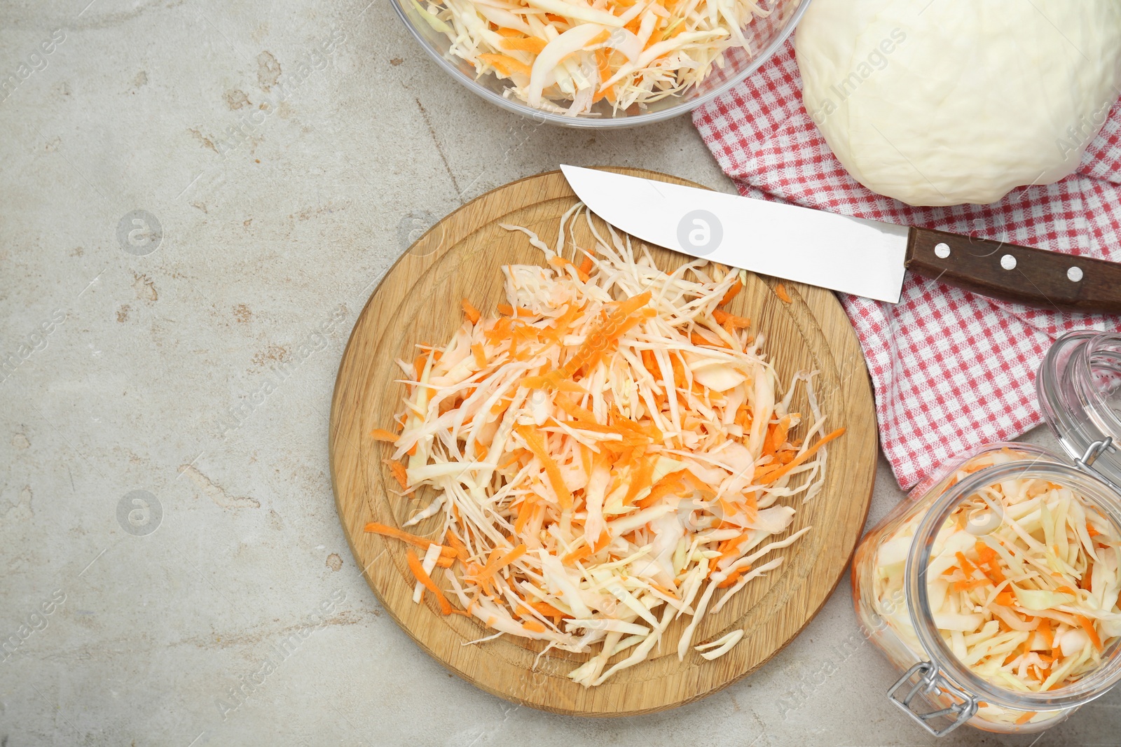 Photo of Cooking delicious sauerkraut soup. Fresh chopped carrot and cabbage on light grey table, flat lay