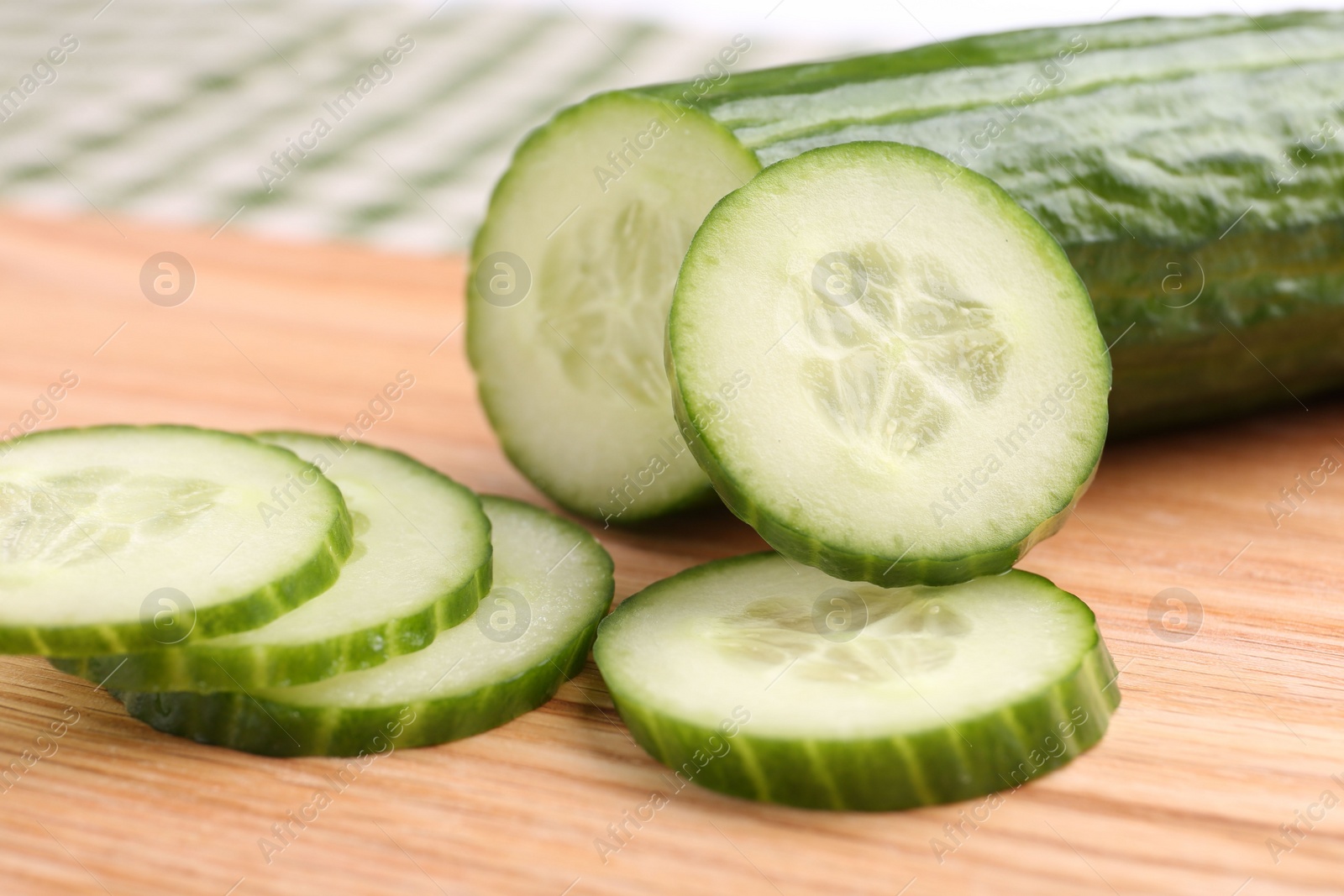 Photo of Cut ripe cucumber on wooden board, closeup