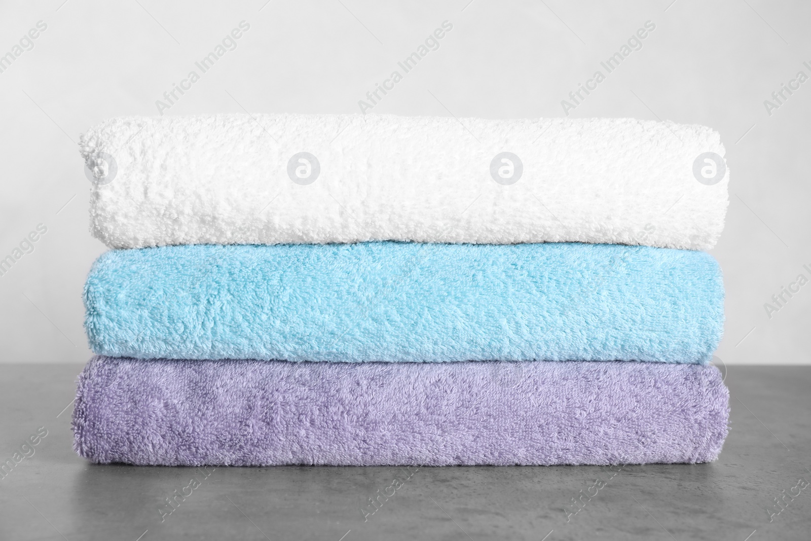 Photo of Stack of clean fresh towels on grey table