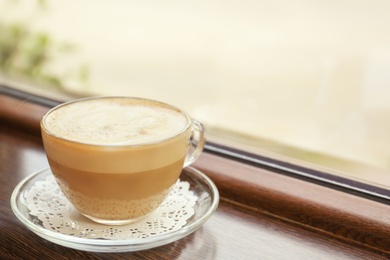 Photo of Cup of delicious aromatic coffee on window sill