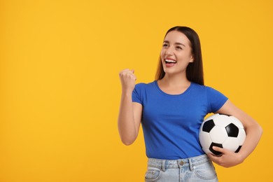 Photo of Happy fan holding soccer ball and celebrating on yellow background, space for text