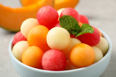 Melon balls and mint in bowl on grey table, closeup