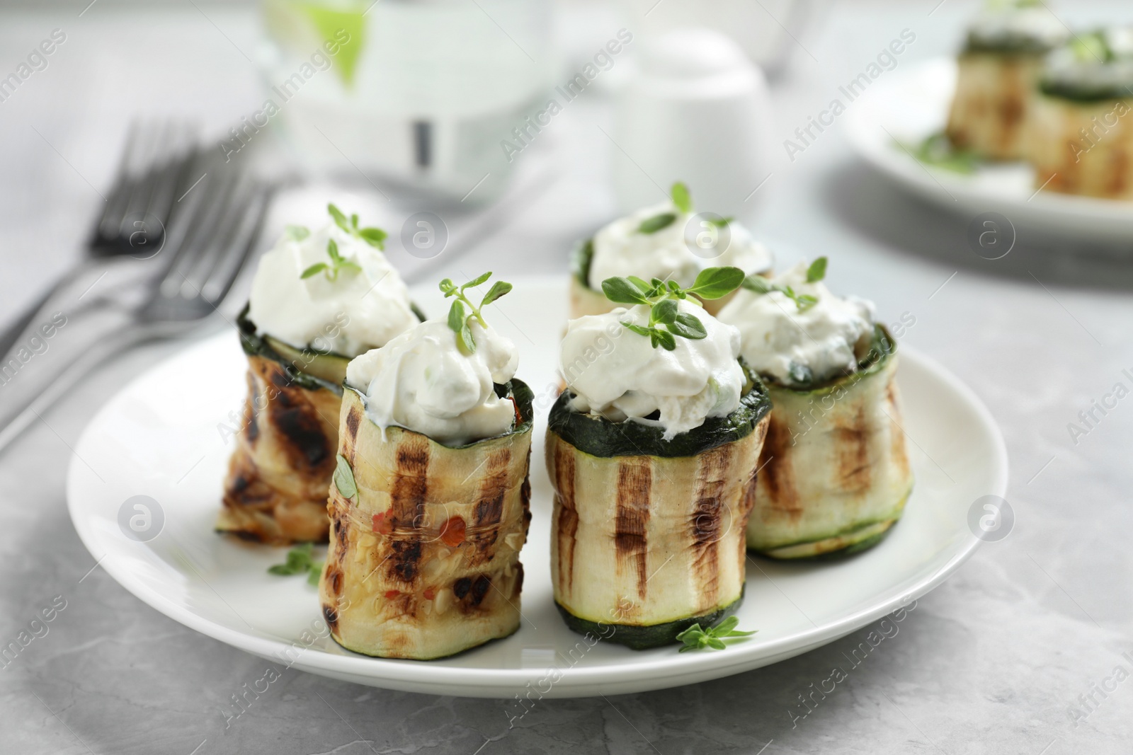 Photo of Tasty stuffed zucchini rolls on grey marble table