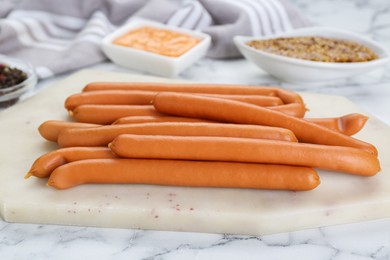 Fresh delicious sausages on white marble table