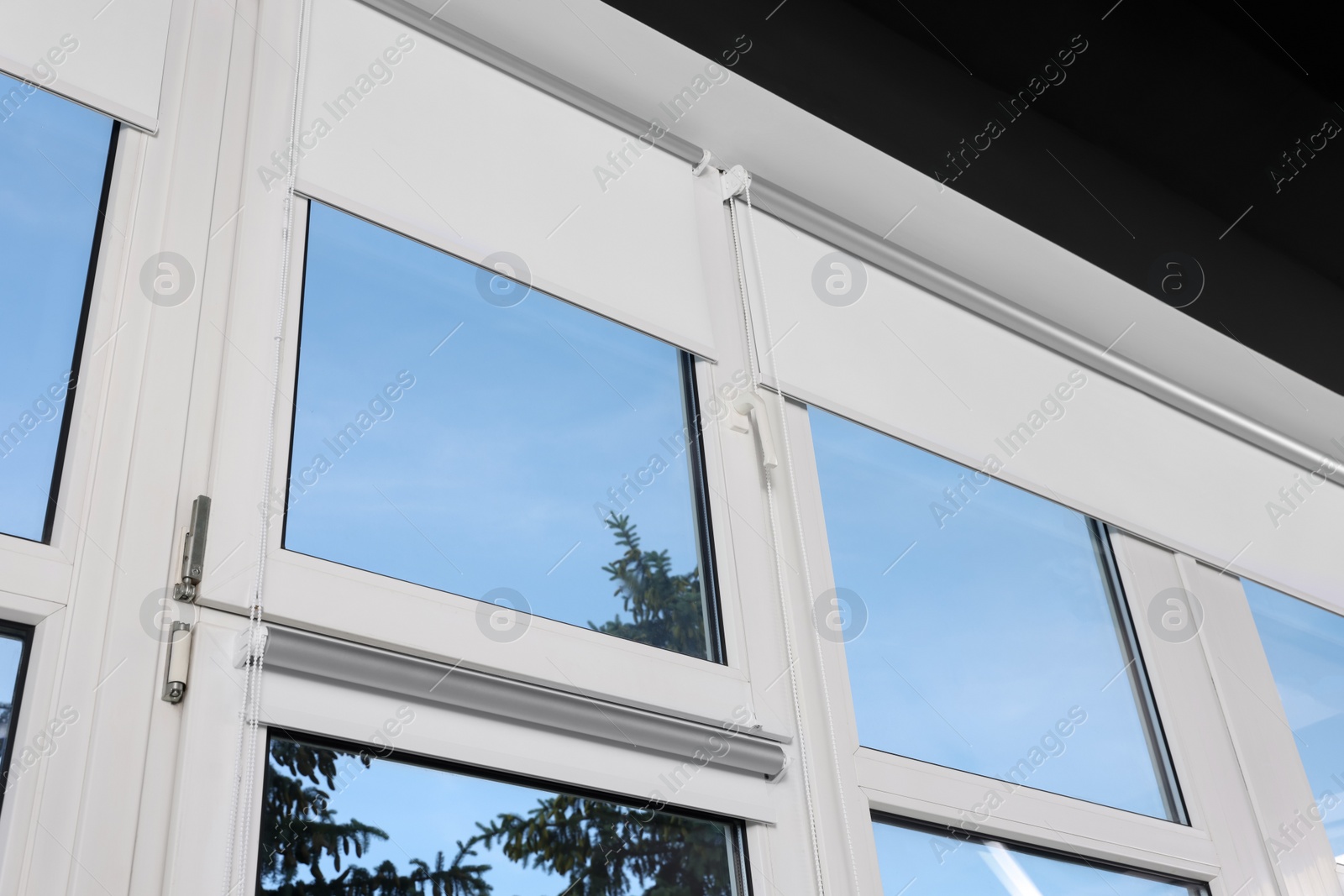 Photo of Window with open white roller blinds indoors, low angle view