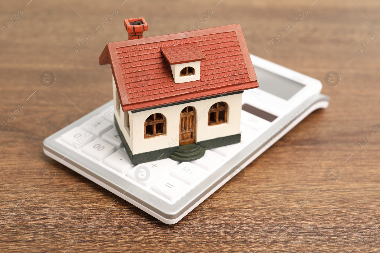 Photo of Mortgage concept. House model and calculator on wooden table, closeup