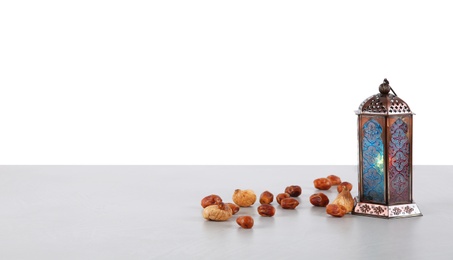 Photo of Muslim lamp and dates on table against white background. Space for text