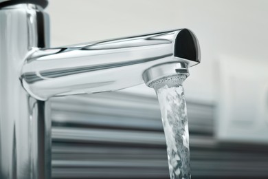 Water flowing from tap on blurred background, closeup