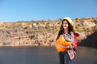 Female camper with sleeping bag near beautiful lake. Space for text