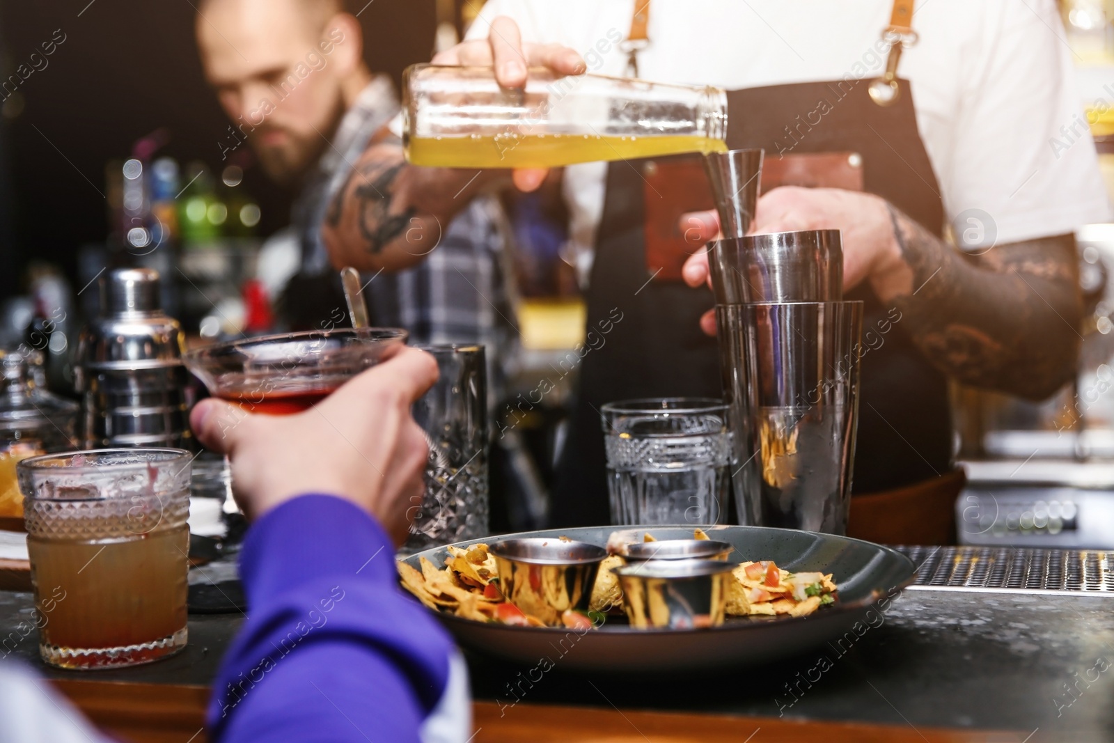 Photo of Bartender preparing tasty cocktail at counter in nightclub, closeup