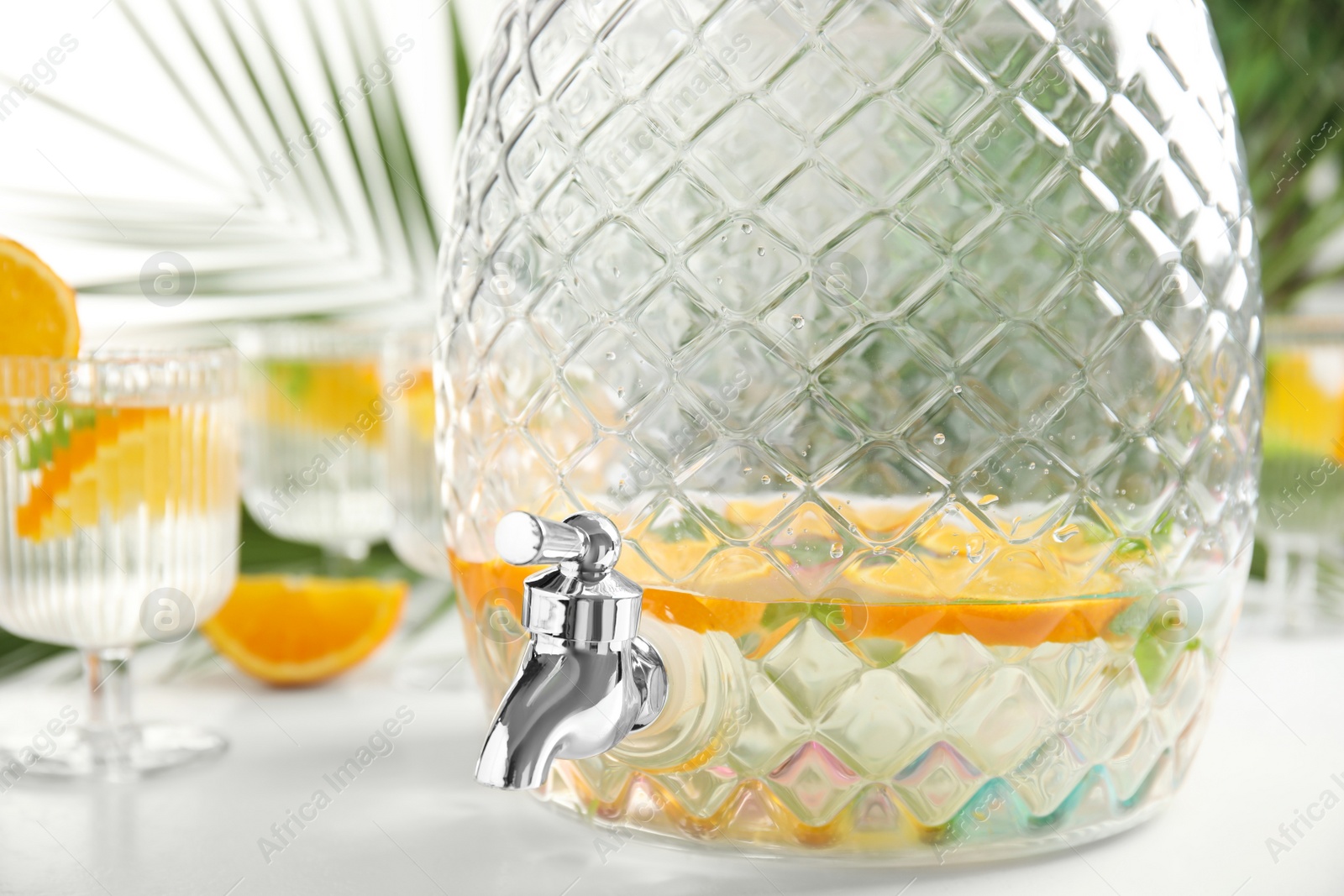 Photo of Beverage dispenser with delicious refreshing drink on white table, closeup