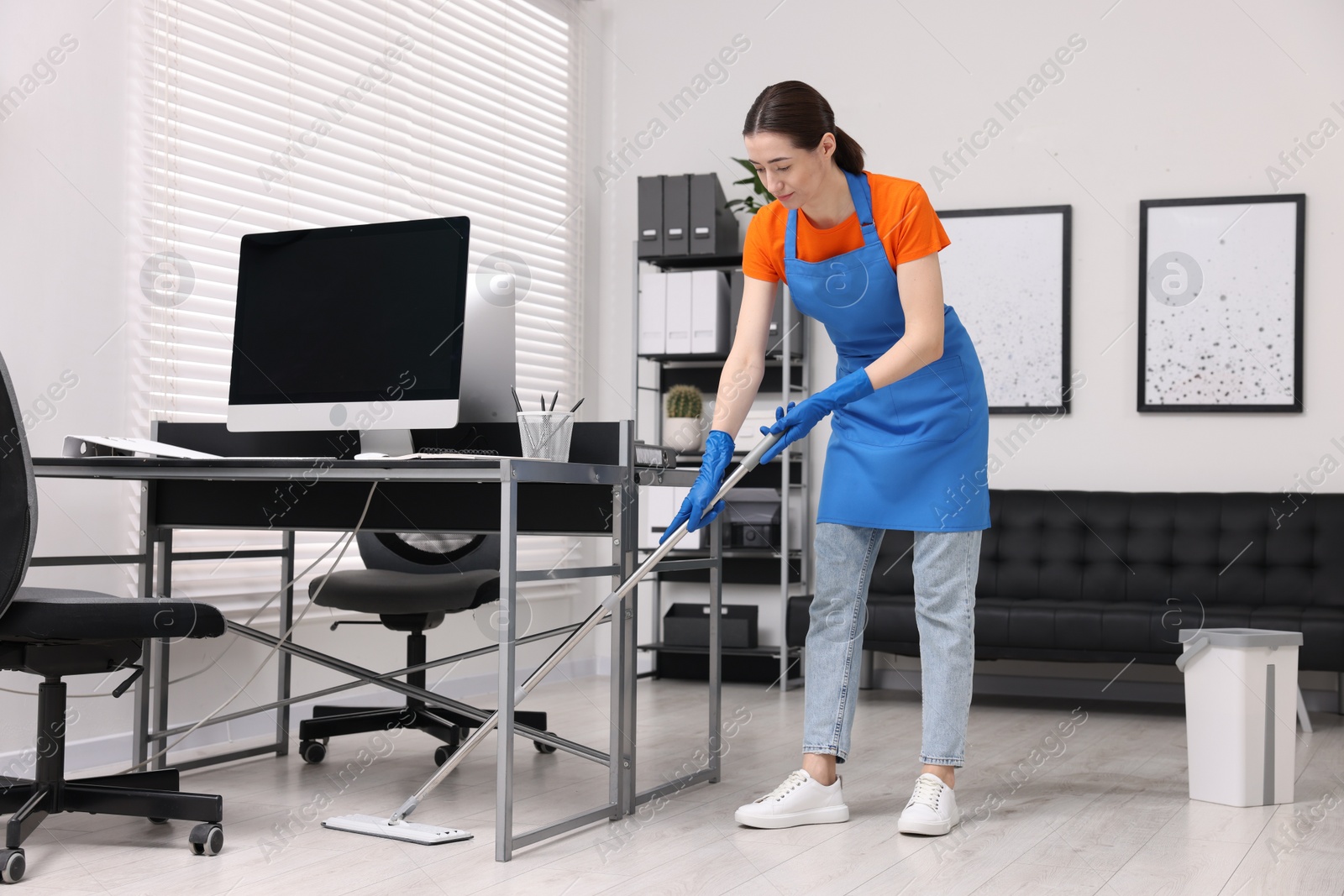 Photo of Cleaning service. Woman washing floor with mop in office