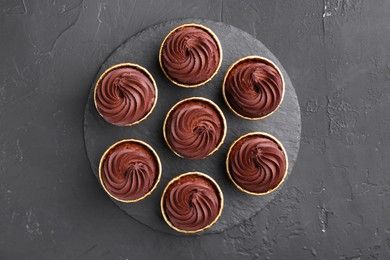 Delicious chocolate cupcakes on black textured table, top view