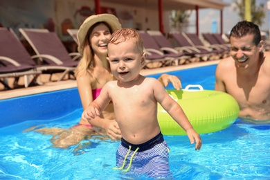 Happy family with little child in swimming pool outdoors