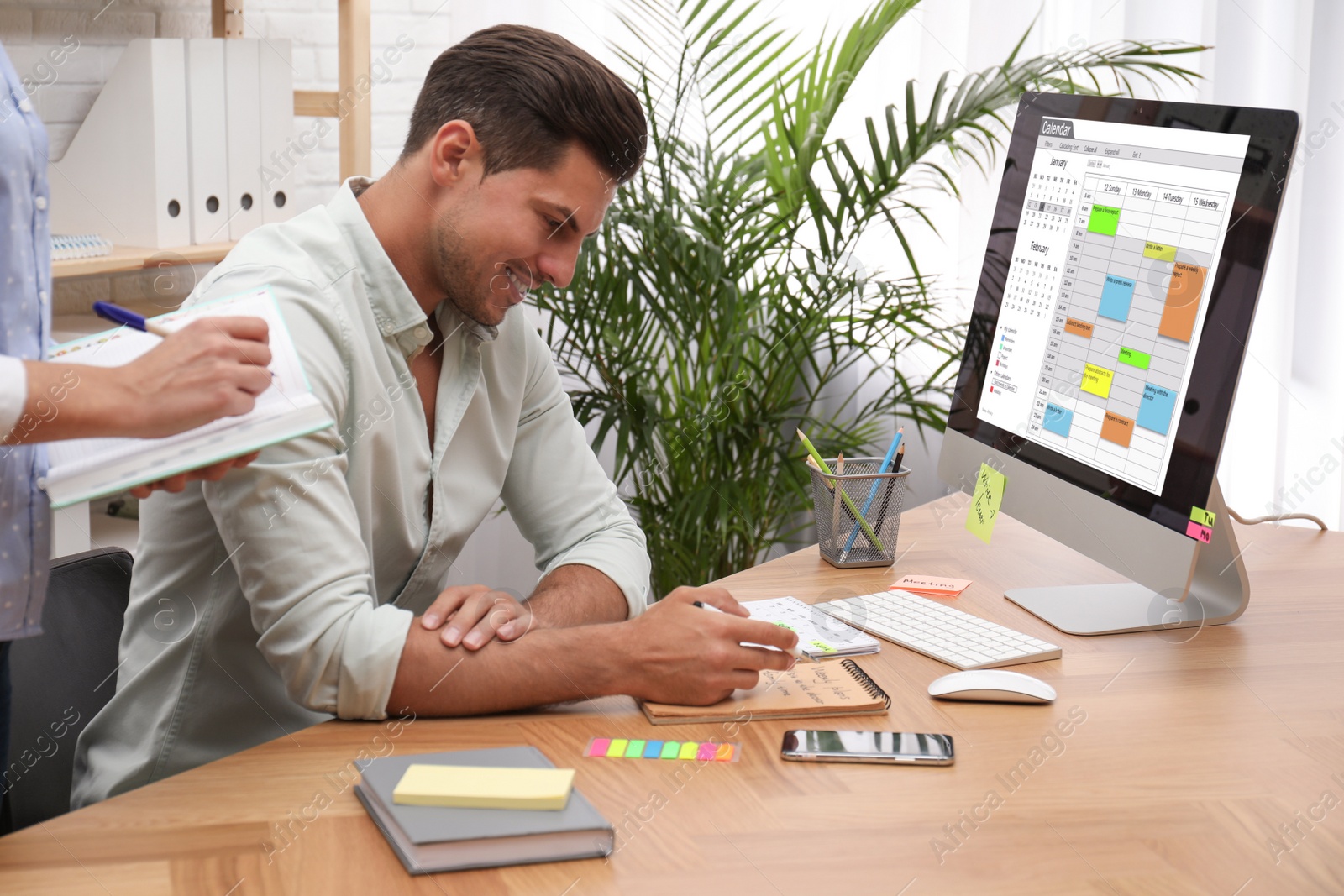 Photo of Colleagues working with calendar app on computer in office