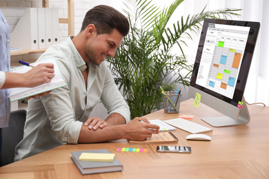 Colleagues working with calendar app on computer in office