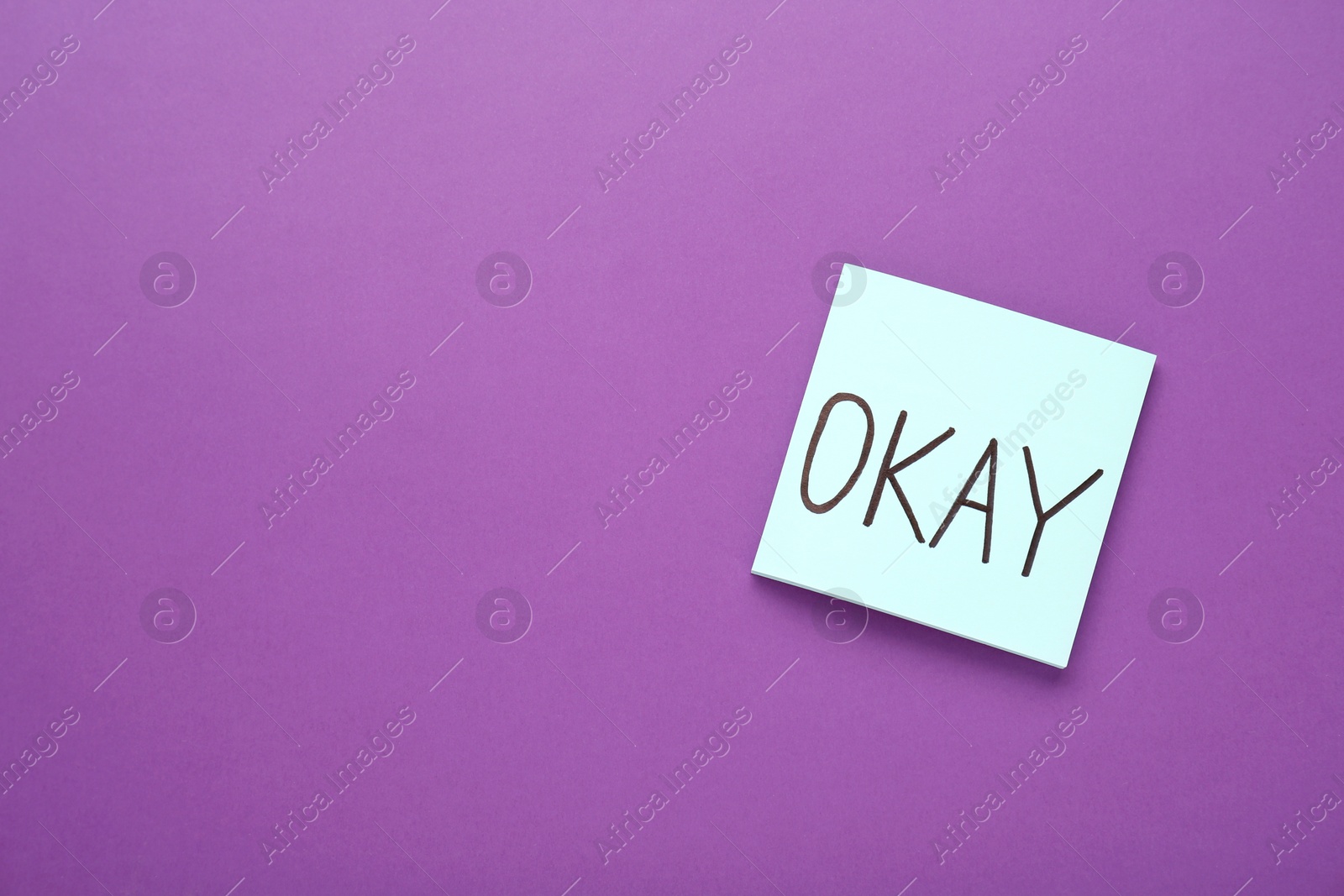 Photo of Note with word Okay on purple background, top view. Space for text