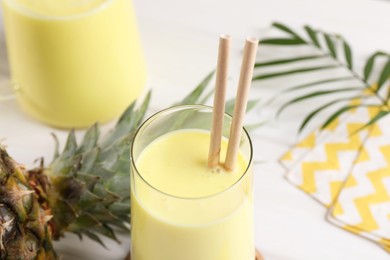 Photo of Tasty pineapple smoothie on white table, closeup