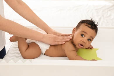 Photo of Mother and her cute child on changing table. Baby massage and exercises