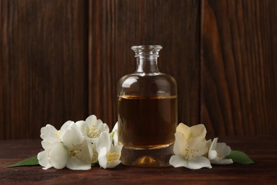 Photo of Essential oil and jasmine flowers on wooden table