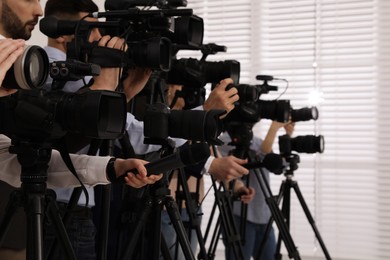 Photo of Group of journalists with cameras waiting for official person indoors, closeup